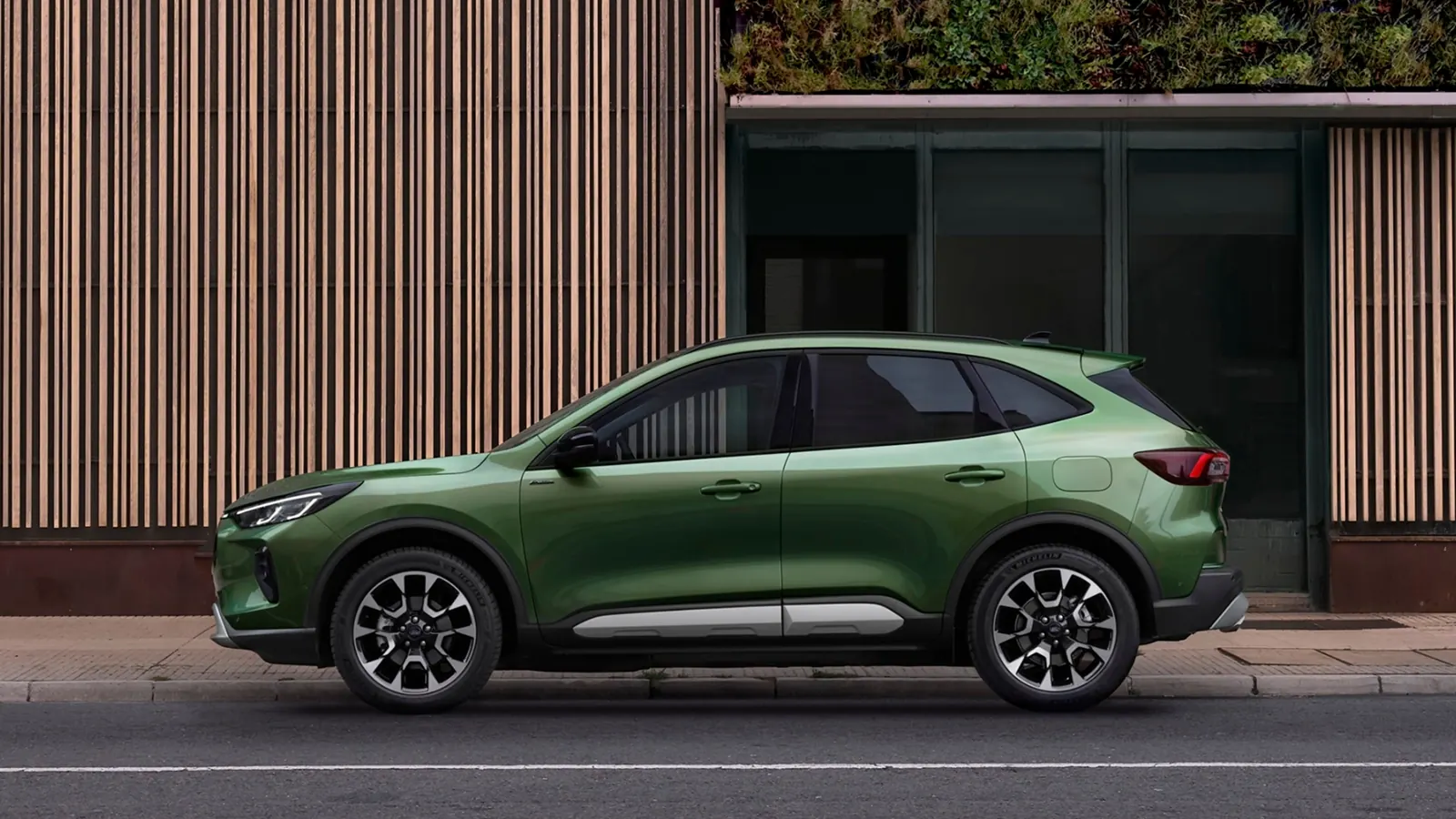 Ahşap cephe önünde yeşil Ford Kuga yandan görünüm